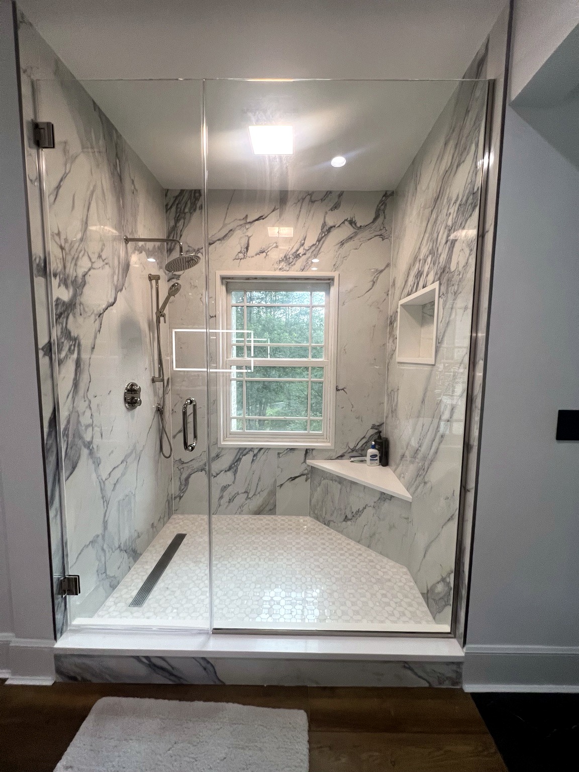 Bathroom renovation with marble-look shower walls and glass enclosure